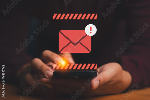 Person holding smartphone with red email alert icon, symbolizing spam warning, phishing notification, data security risk, and online communication alert in cybersecurity and digital safety concept.