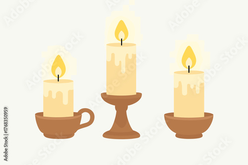 Set of three burning candles in various brown holders casting a warm glow