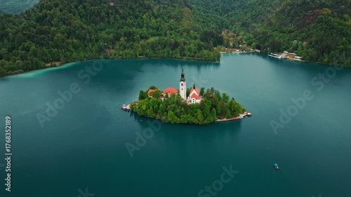Aerial view of Church of the Assumption of Mary in the center of the lake Bled. Flying around small island on Bled Lake in Slovenia