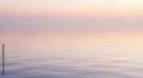 Serene view of a calm ocean surface under a pastel-colored twilight sky, creating a tranquil and peaceful atmosphere.