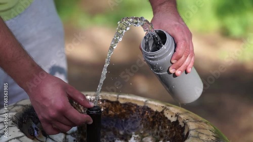 Close up of male hands filling a bottle with drinking water in a public drinking fountain