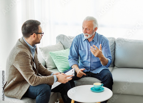 Senior man having a meeting with an agent, businessman, salesperson or doctor in his office