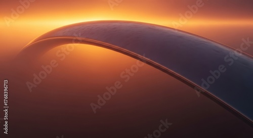 An elegant curved architectural structure silhouetted against a vibrant orange and yellow sunset sky, creating a stunning visual composition.