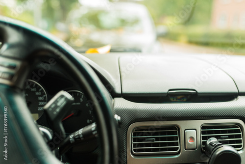 Close-up shot of a car steering wheel and dashboard in daylight. The photo captures the details of a clean and functional vehicle interior, perfect for illustrating driving, travel, or