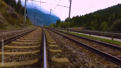 A time lapse low angle view of train tracks riding across the kandertal valley in switzerland on a cloudy day