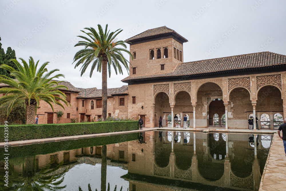 Fototapeta premium Granada, Spain - 21 Oct 2025: Partal Palace and pond at the Nasrid Palaces, Alhambra
