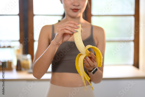 фотографія Closeup activity woman eating banana in kitchen