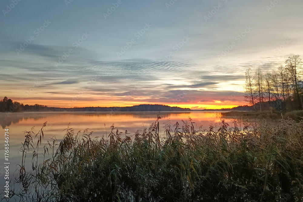 Obraz premium A beautiful sunrise on a calm lake in Finland. A colorful, quiet Finnish morning