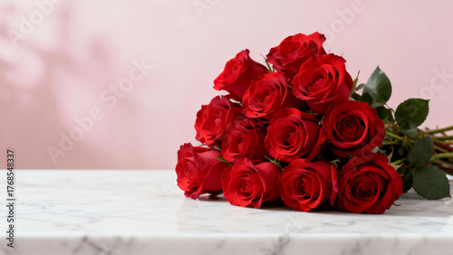 Fototapeta Naklejka Na Ścianę i Meble -  A dozen long-stemmed red roses lie on a white marble surface, set against a soft pink background with shadow texture. This romantic image symbolizes love and passion.
