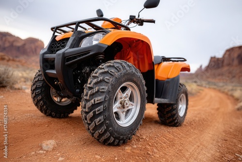 An orange all-terrain vehicle parked on a dirt trail surrounded by desert scenery. Ideal for outdoor adventure themes.