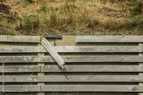 Fotografie Old broken wooden fence with dry grass.