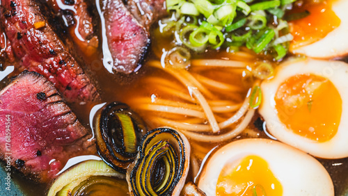 Succulent rare beef ramen in a beautiful bowl with bamboo shoots, spring onions, tamago (Japanese marinated egg), and leeks. Rich broth, authentic Japanese flavors.