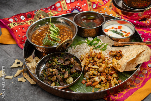 Vegetarian Indian thali on banana leaf consisting  of rice, dal, rasam, and a variety of curries