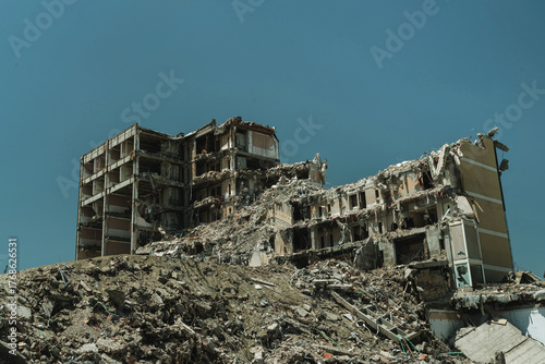 Destroyed residential building surrounded by piles of debris because of demolition, earthquake, war attack or large-scale structural failure.