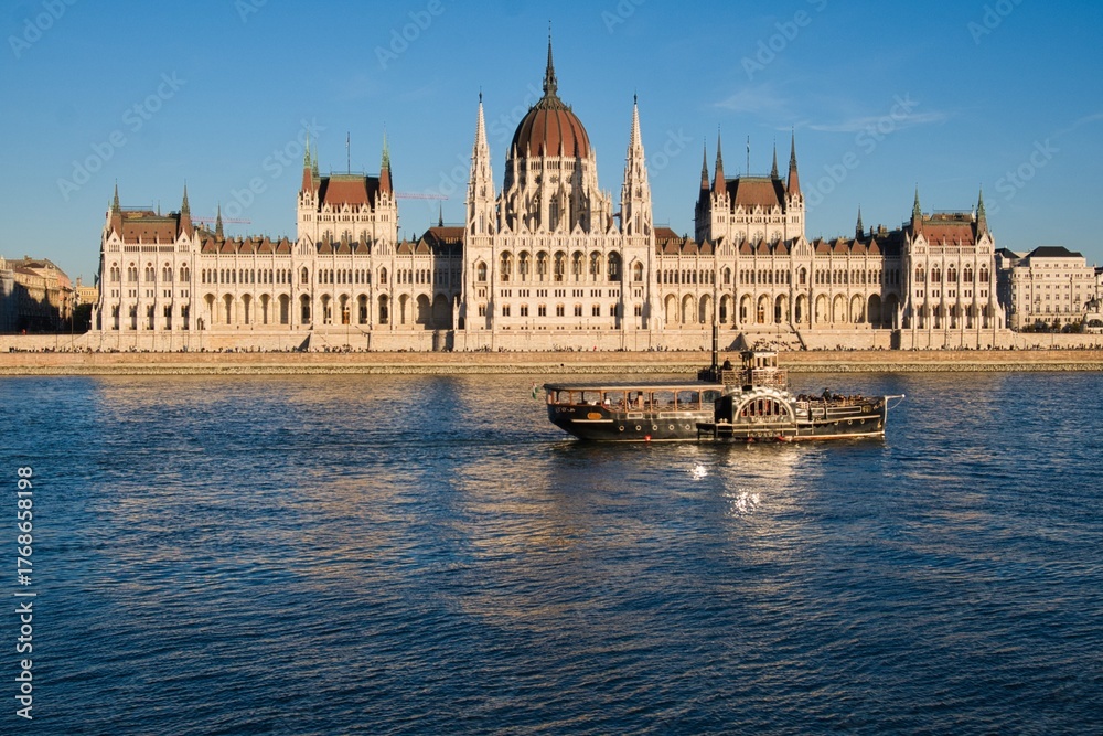 Naklejka premium Hungarian Parliament Building during sunset with a boat