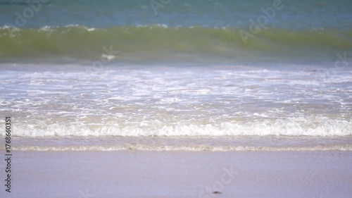 Gentle ocean waves rolling onto sandy beach under bright sunlight creating a calm relaxing and natural coastal mood
