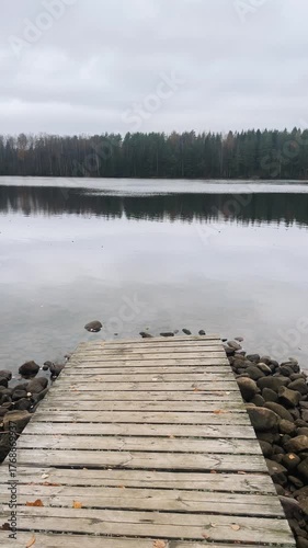 Serene lake view with wooden pier and lake. Calm autumn atmosphere. Vertical video