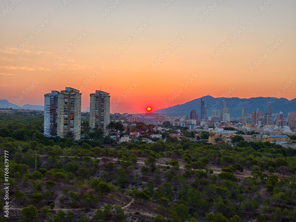 Obraz premium A stunning sunset casts beautiful colors over an urban landscape with lush greenery