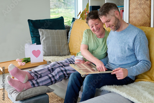 Senior Mum Sharing Photograph Album Memories with Mature Son