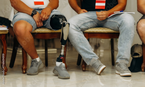 Man with prosthetic leg sitting among people, social inclusion concept