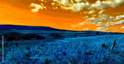 The sky burns orange above Hillings Lane, a blaze of dusk spilling over blue moorland and fields. Clouds drift like ash, soft, scattered, etching depth into the Yorkshire air in Ilkley, UK