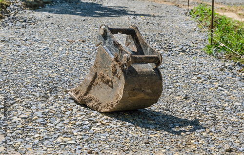 Konzept Erdarbeiten und Landschaftsbau: Seitenansicht einer großen Bagger Schaufel auf einer Baustelle vor Aushub mit viel Freiraum für Textgestaltung
