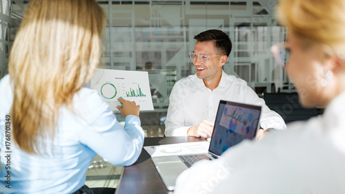 Team discussing data insights in a modern office setting with laptops and charts present
