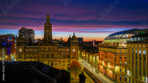Glasgow City Chambers, landmark architecture, and George Square in Glasgow, Scotland, United Kingdom, aerial view illuminated by the purple clouds at twilight.