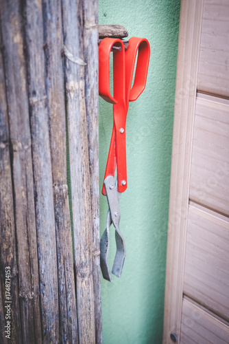 Hanging Red Garden tongs Against Green Wall