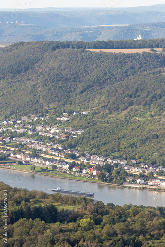 Scenic view of the Rhine River near Bad Salzig in Germany with a cargo ship navigating the waterway and lush hills in the background