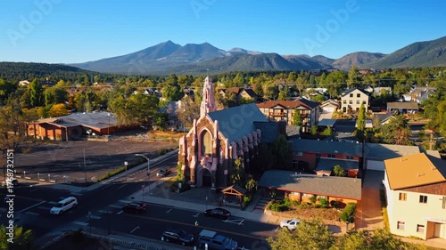 Approaching a beautiful church in Flagstaff, Arizona, USA. Amazing scenery of green cityscape and sunlit verdant mountains from drone.