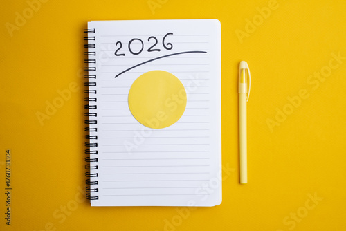 Happy New Year 2026 and a notepad on a colored background. Layout for writing annual business plans, schedules, as well as New Year's resolutions and goals.  
