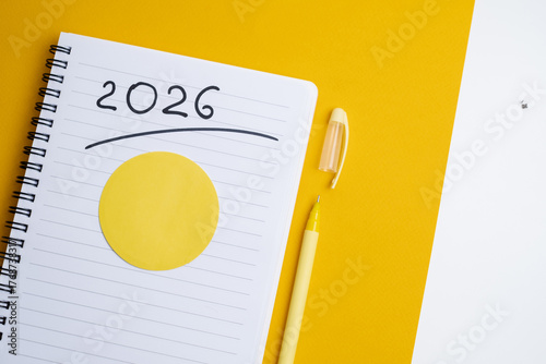 Happy New Year 2026 and a notepad on a colored background. Layout for writing annual business plans, schedules, as well as New Year's resolutions and goals.  