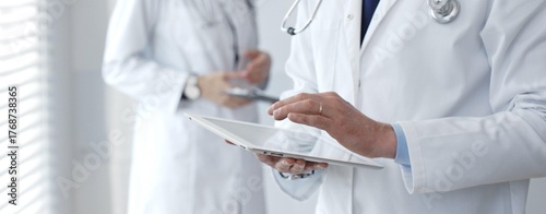 Photos Doctors working together on medical records while a healthcare professional uses