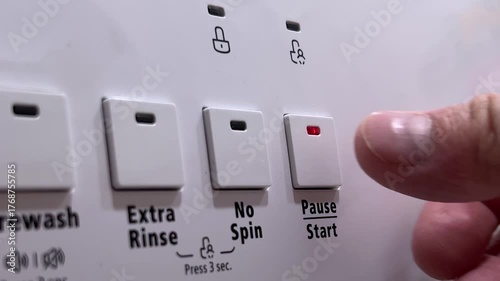 Horizontal video close up. Male hand presses Start and Pause button on control panel of white wash machine in home bath room. Concept of house work, washing clothes, jeans, bed linen, t-shirt, spin