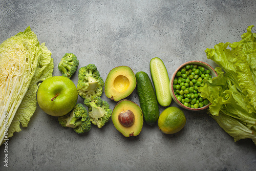 Fresh green vegetables and fruit grey concrete background top view, diet, vegetarian. Set of different green healthy products, clean eating