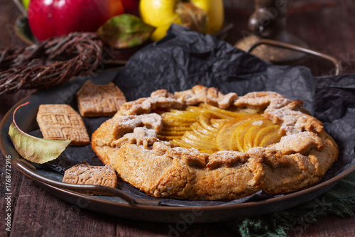 Apple galette, gingerbread houses, and apples on a wooden background.