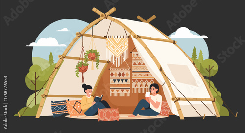 Two women relax in a cozy, bohemian-style glamping tent outdoors. One reads a book, the other sips a drink