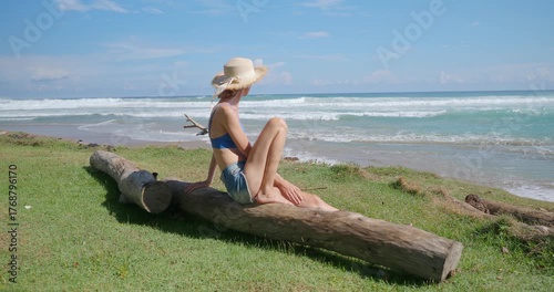 Woman enjoying nature, looking at ocean with big waves in tropical environment.