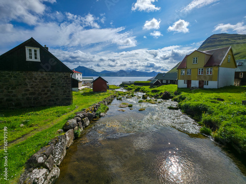 Scenic village with colorful houses and river flowing toward the fjord