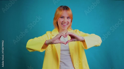 Happy young woman smiling and showing a heart hand gesture