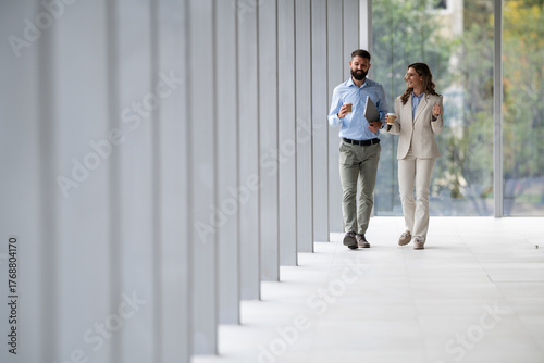 Business colleagues walking and talking in office hallway