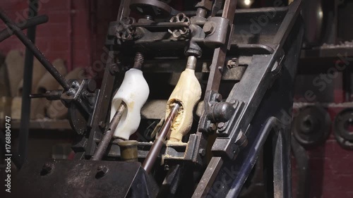Industrial copy lathe shaping a wooden clog from raw block by following plastic mold with rotating cutters, traditional Dutch shoes