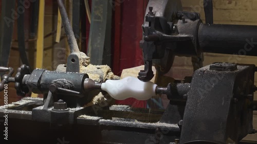 Industrial copy lathe shaping a wooden clog by tracing mold contours with rotating blades and flying sawdust
