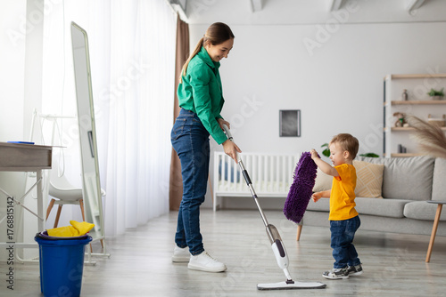 Fotografija A parent and young child are tidying up their modern living room