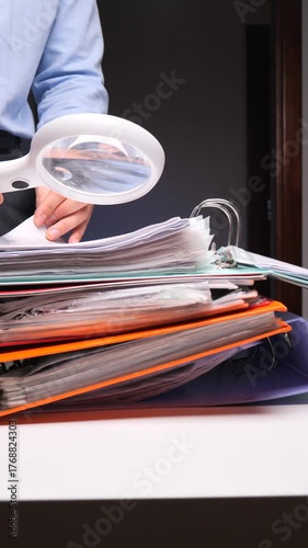 vertical video Person examining documents with magnifying glass investigating data