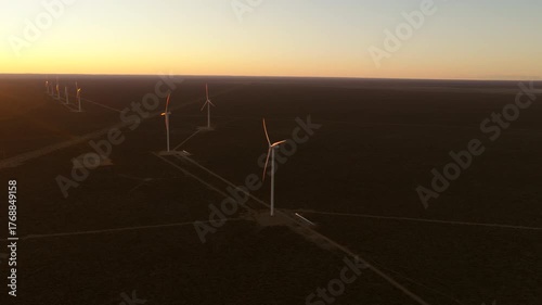 Aerial view of wind turbines spinning over a vast landscape during sunset in Patagonia, Argentina.