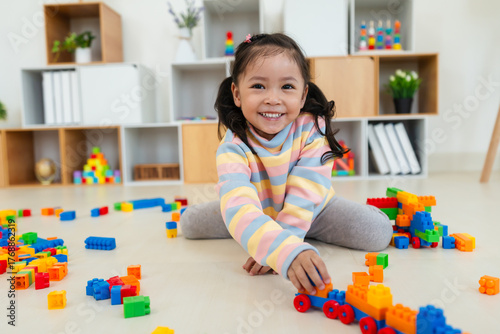 toddler girl playing building blocks or plastic bricks toy at home