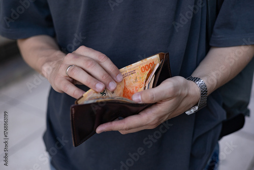 Foto Male hands counting Argentine peso 1000 banknotes in open wallet
