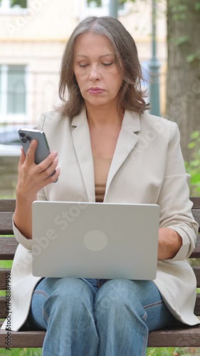 Old Senior Woman Working on Smartphone and Laptop in Park